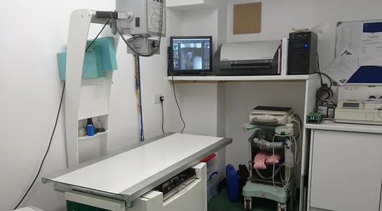 Radiology room with X-ray table, imaging equipment, and a computer monitor.